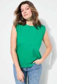 Groene t-shirt met korte mouwen, ronde hals en een relaxte pasvorm, gemaakt van gladde katoenstof. Gemaakt in combinatie met lichtblauwe denim jeans.