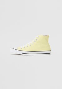 Gelber High-Top-Sneaker aus Canvas mit weißen Schnürsenkeln, Gummizehenkappe und schwarzen Streifenakzenten entlang der Sohle.