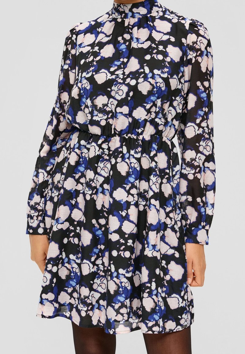  långärmad klänning med hög krage, prydd med svart tyg med ett blommönster i blått och rosa. Elastisk midja, knälång.