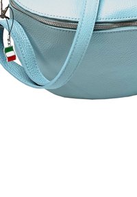Lichtblauwe, gestructureerde leren tas met een ronde vorm, zilveren rits en een kleine sleutelhanger met de Italiaanse vlag.