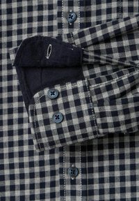 Koszula zapinana na guziki w czarno-szary wzór w kratę. Bawełnowy materiał z niebieskimi guzikami i kontrastowymi granatowymi mankietami.