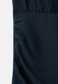 Donkerblauwe stof met een gestructureerd oppervlak en duidelijke plooien aan één zijde, die zorgen voor een dynamisch designelement.