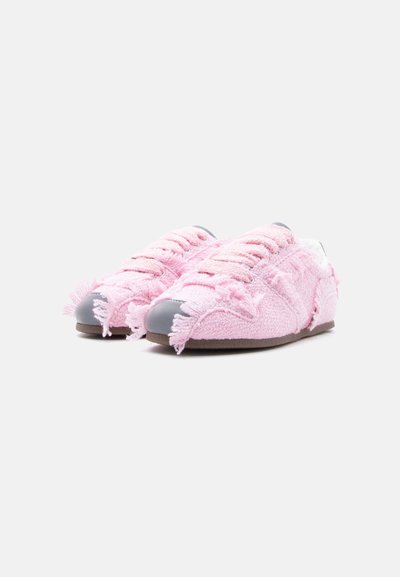 Paire de baskets roses texturées avec bords effilochés et bouts gris sur un fond gris clair.