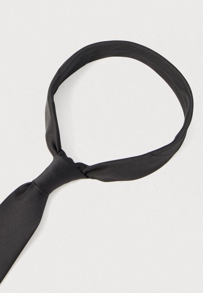 Juodas šilkinis kaklaraištis, lygios tekstūros, siauro silueto, surištas mazgu, su subtiliu dryžuotu raštu. Tinka oficialiems renginiams.