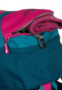 Zunanji nahrbtnik v teali in roza z delno odprtim zgornjim žepom, v katerem leži zvit roza in vzorčan volneni kos oblačila.