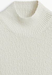 Pull en tricot blanc à col montant avec un motif texturé et un col côtelé, offrant une apparence chaleureuse grâce à un tissu doux et respirant.