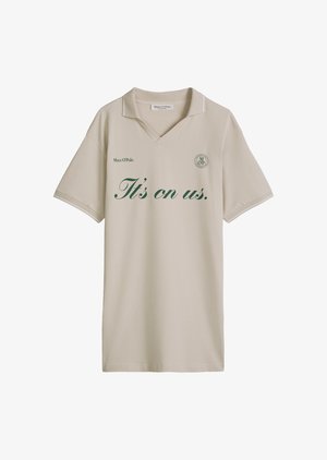 Beżowa koszulka polo z krótkim rękawem z zielonym napisem "It's on us." i logo Marc O'Polo na piersi, z małym kołnierzykiem i dekoltem w serek.