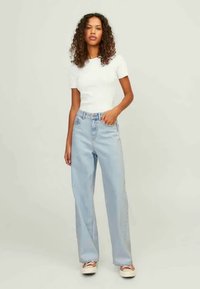 White fitted t-shirt, light blue high-waisted straight-leg jeans, paired with light-colored shoes, on a neutral background.