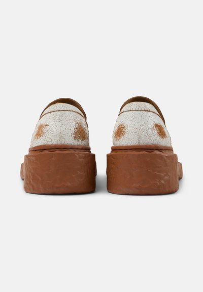 Hvide teksturerede sko med en sprukken finish, der har brune accenter og en tyk brun sål. Runde former med en slip-on design.