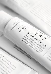 Barrierekrem tube med hvitt plastskall, svart tekst. Har «147» tydelig fremhevet, med ingrediensdetaljer trykket på en glatt, matt overflate.
