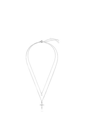 Collier double chaîne en argent avec une petite gemme ronde sur la chaîne supérieure et un pendentif croix orné de cristaux sur la chaîne inférieure.