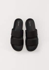 Sandale negre cu talpă plată, având două curele texturate și un interior neted, cu un logo încorporat pe talpă. Talpa plată asigură confort.
