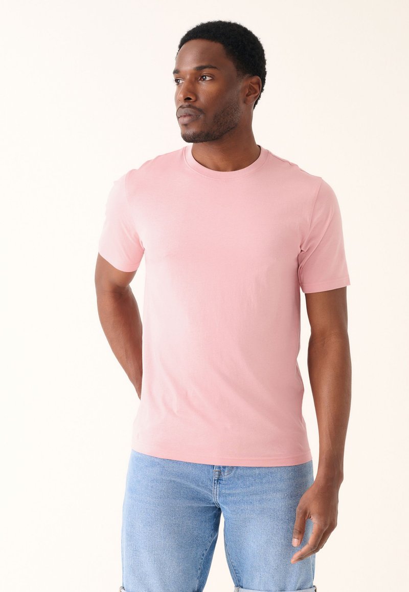 Lyserød bomulds-T-shirt med korte ærmer, rund halsudskæring og en glat tekstur. Kombineret med lyseblå denimshorts.