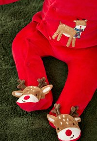 Roter Samt-Overall mit einem Rentierdesign, das einen Schal und Knopfverschlüsse aufweist, ergänzt durch rentiereförmige Fußakzente.