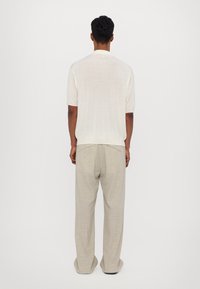 Chemise courte à manches courtes beige clair, à coupe décontractée, assortie à un pantalon large texturé gris clair. Design simple, sans marque visible.