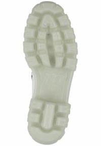Suela de zapato con un diseño de goma translúcida y gruesa. Presenta patrones de rodadura profundos para tracción y un detalle de logo en relieve.