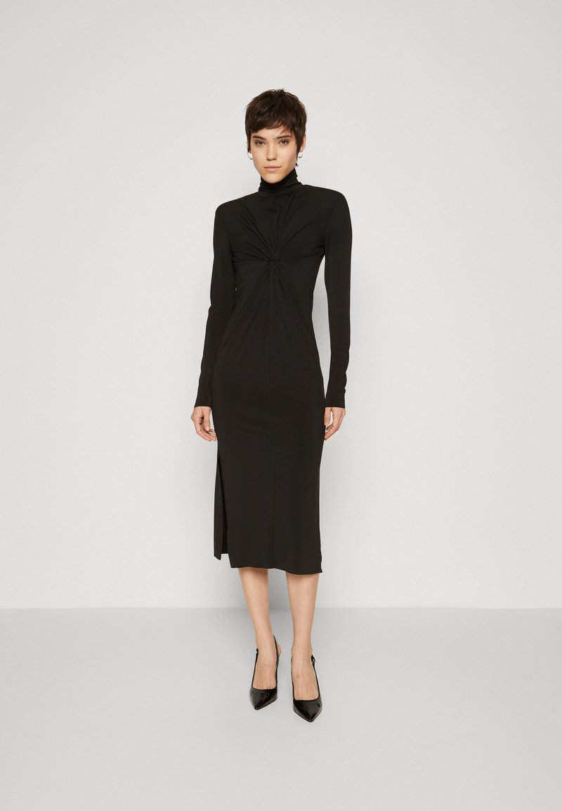 Robe longue noire à manches longues avec un col haut, un détail frontale torsadé et une longueur mi-mollet, fabriquée en tissu lisse et extensible.
