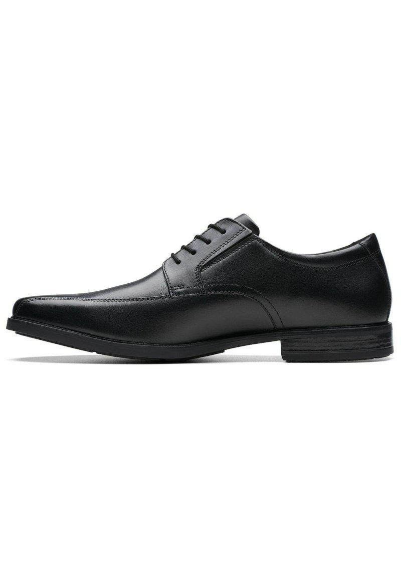 Scarpa da uomo in pelle nera con punta affilata, sei fori per i lacci e tacco basso impilato. Texture liscia con dettagli di cucitura sottili.