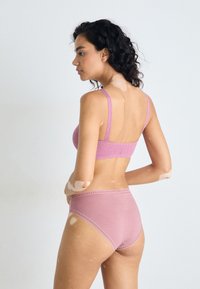 Pink lingerie set featuring a textured, patterned bralette and high-waisted underwear with lace trim, set against a neutral background.