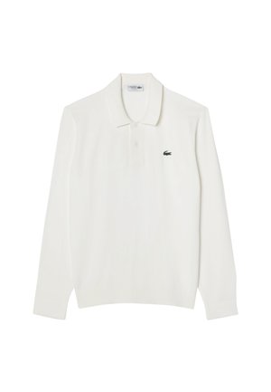 Camisa polo blanca de manga larga con un cuello clásico, que presenta un pequeño logo verde de Lacoste en el área izquierda del pecho. Tejido de algodón.