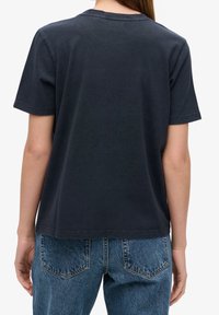 Mörk marinblå bomulls t-shirt med avslappnad passform, rund halsringning, korta ärmar och rak fåll, i kombination med högmidjade denimjeans.