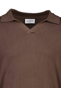 Ruskea lyhythihainen polo-paita, jossa on V-pääntie ja ribbauskaulus. Kangas näyttää sileältä ja kevyeltä, ja se on slim fit -mallinen.