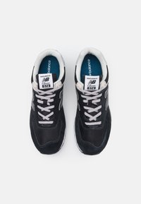 Czarne zamszowe i siatkowe sneakersy z szarymi akcentami, z wyraźnym logotypem "N", sznurowadłami i wyściełanym kołnierzem.