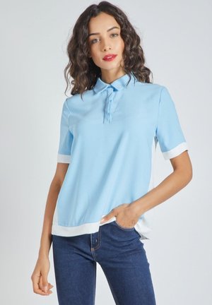 Polo de color azul claro con cuello, mangas cortas y detalles blancos en los puños y el dobladillo. Textura de tela suave.