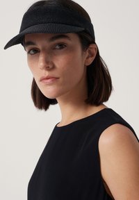 Svart skärm med strukturerad tyg och bred skärm. Modellen bär en ärmlös svart topp som framhäver rena linjer och mjuk textur.