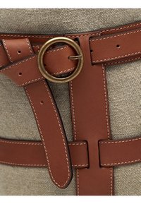 Cintura in pelle marrone con cuciture bianche presenta una fibbia rotonda in ottone, allacciata su uno sfondo di tessuto beige testurizzato.