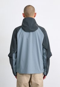 Lightweight jacket featuring blue-grey fabric with darker grey accents, a hood, and a relaxed fit. Smooth texture with raglan sleeves.