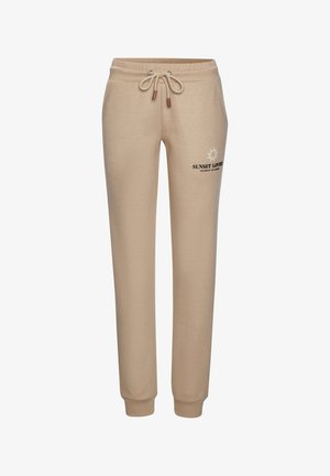 Beige trainingsbroek met elastische tailleband en trekkoord, boorden bij de enkels, zijzakken en "Sunset Lovers" tekst met zonafbeelding op de linker dij.