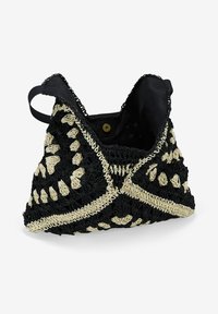 Bolso tejido en negro y crema con un diseño de crochet texturizado, que presenta una forma triangular, doble asa y un patrón decorativo.