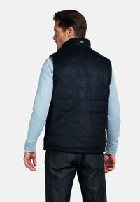 Marineblauer gesteppter Weste mit hohem Kragen, aus weichem Material gefertigt. Verfügt über eine glatte Textur und ein kontrastierendes hellblaues Langarmshirt darunter.