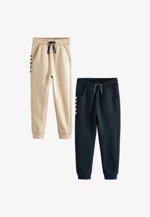 Two pairs of jogger pants: one beige, one navy. Both feature elastic waistbands, pockets, and distinct triangular panel designs.