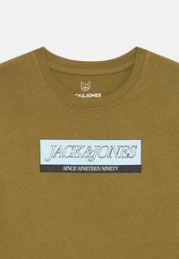 Olivengrønn crewneck t-skjorte med et rektangulært logo-patch som leser "JACK & JONES" og "SINCE NINETEEN NINETY" i svart og lyseblå.