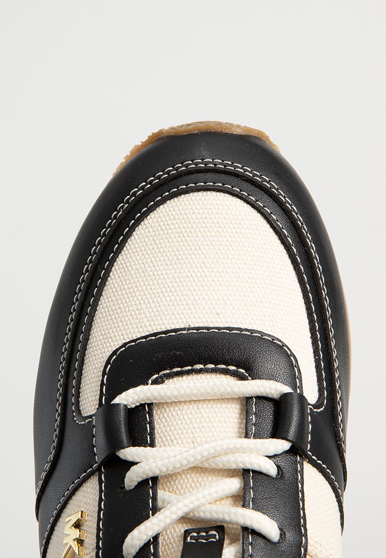 Vita canvas sneakers med svarta läderdetaljer, rund tå, tjock gummisula och vita snören. Har kontrasterande sömnadsdetaljer.