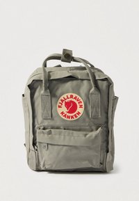 Harmaa Fjällräven Kånken -reppu, jossa on pyöreä punainen logo, pehmustetut kantokahvat, etutasku vetoketjulla ja kestävä kangas. Kompakti suorakulmion muotoinen malli.