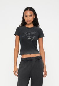 Korte zwarte cropped T-shirt met de tekst "Forever Hugo" in een glanzend schrift, gemaakt van een zachte, rekbare stof met korte mouwen.