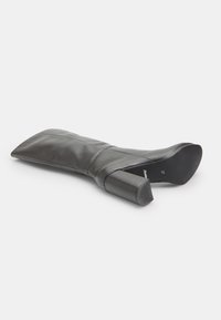 Cizmă de gleznă din piele neagră, cu vârf ascuțit și toc pătrat. Partea superioară are o textură netedă și detalii cusute pe lateral.