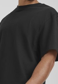 Black cotton T-shirt with a round neckline, short sleeves, and a relaxed fit. Soft texture, minimalistic design, no visible patterns or accents.