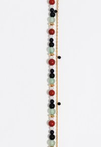Multikleurige kralenarmband met rode, groene, zwarte en witte stenen, verfraaid met gouden hardware en een delicate ketting.