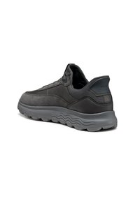 Sneaker bassi neri e grigi scuri con colletto imbottito, suola in gomma testurizzata e motivo a onde sulla suola intermedia, vista angolata dal lato posteriore destro.
