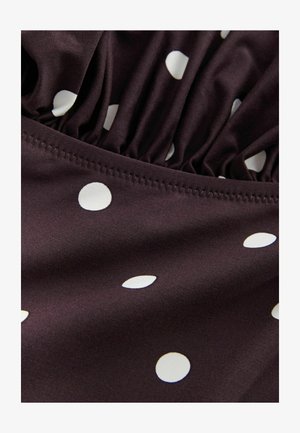 Brūns audums ar baltām punktiņām; gar malu ir savilkta auduma tekstūra un kārtīga šūšana. Gluda, mīksta tekstūra.