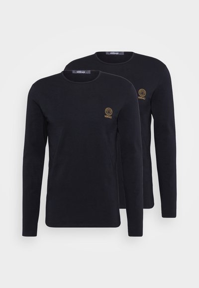 Melni garie piedurkņu t-krekli, kas izgatavoti no kokvilnas, ar apaļu dekoltē un mazu izšūtu zelta logotipu uz krūtīm. Attēlotas divas kreklas.