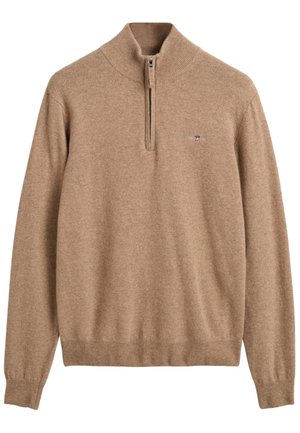 Beige ylletröja med hög krage och kvartdragkedja, med ribbade muddar och nederkant, samt en liten logotyp på bröstet.