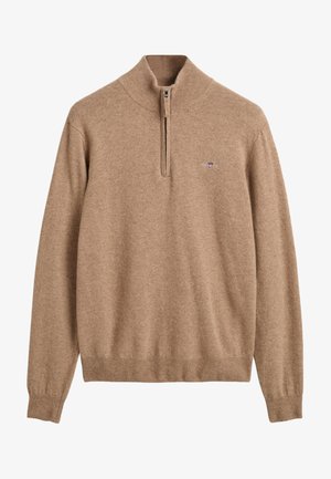 Pull en laine beige avec un col montant et une fermeture éclair quart de zip, présentant des poignets et un ourlet côtelés, avec un petit logo sur la poitrine.