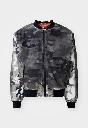 Kamo bunda s bomber strihom v odtieňoch šedej, s predným zipsom, rebrovanými manžetami a jasne oranžovou podšívkou. Obsahuje bočné vrecká.