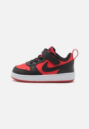 Black and red leather toddler sneakers with a strap, white midsole, red outsole, and black accents. Features a textured surface and a logo.