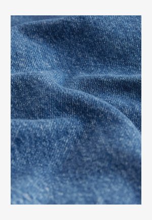 Denimstoff in tiefblau mit einer leicht strukturierten Oberfläche, die sanfte Falten und wellenartige Formen zeigt und das gewebte Muster hervorhebt.